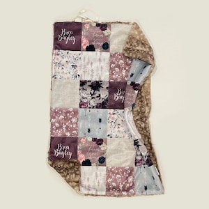 Puede incluir: Una manta suave y mullida para beb&eacute; con un dise&ntilde;o de patchwork que presenta patrones florales, flechas y el nombre "Brea Bayley" en una fuente cursiva. La manta est&aacute; hecha de una combinaci&oacute;n de telas, incluyendo un material suave y peludo en un lado y una tela de algod&oacute;n en el otro.