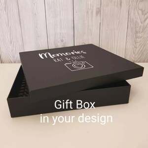 May include: Black gift box with a white inscription that reads "Memories Kat & Ollie" and a camera icon with a heart. The box is open and the lid is propped up. The text "Gift Box in your design" is printed on the bottom of the box.