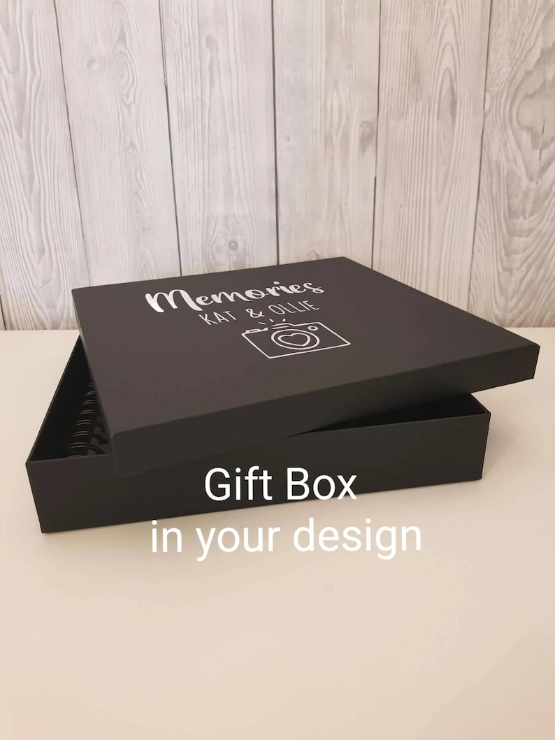 May include: Black gift box with a white inscription that reads "Memories Kat & Ollie" and a camera icon with a heart. The box is open and the lid is propped up. The text "Gift Box in your design" is printed on the bottom of the box.