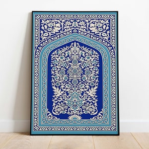Puede incluir: Una impresi&oacute;n enmarcada de una alfombra de oraci&oacute;n isl&aacute;mica tradicional con intrincados patrones florales en blanco y azul sobre un fondo azul oscuro.