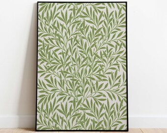May include: A framed art print with a repeating pattern of green leaves on a cream background. The artwork is in a black frame, leaning against a white wall on a wooden floor. The botanical design adds a touch of nature to the room.