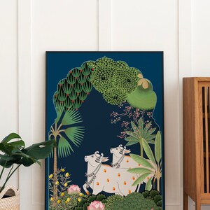May include: A framed illustration of two white cows with orange spots walking through a lush green forest. The cows are adorned with floral garlands and bells. The background is a deep blue with a traditional archway design.
