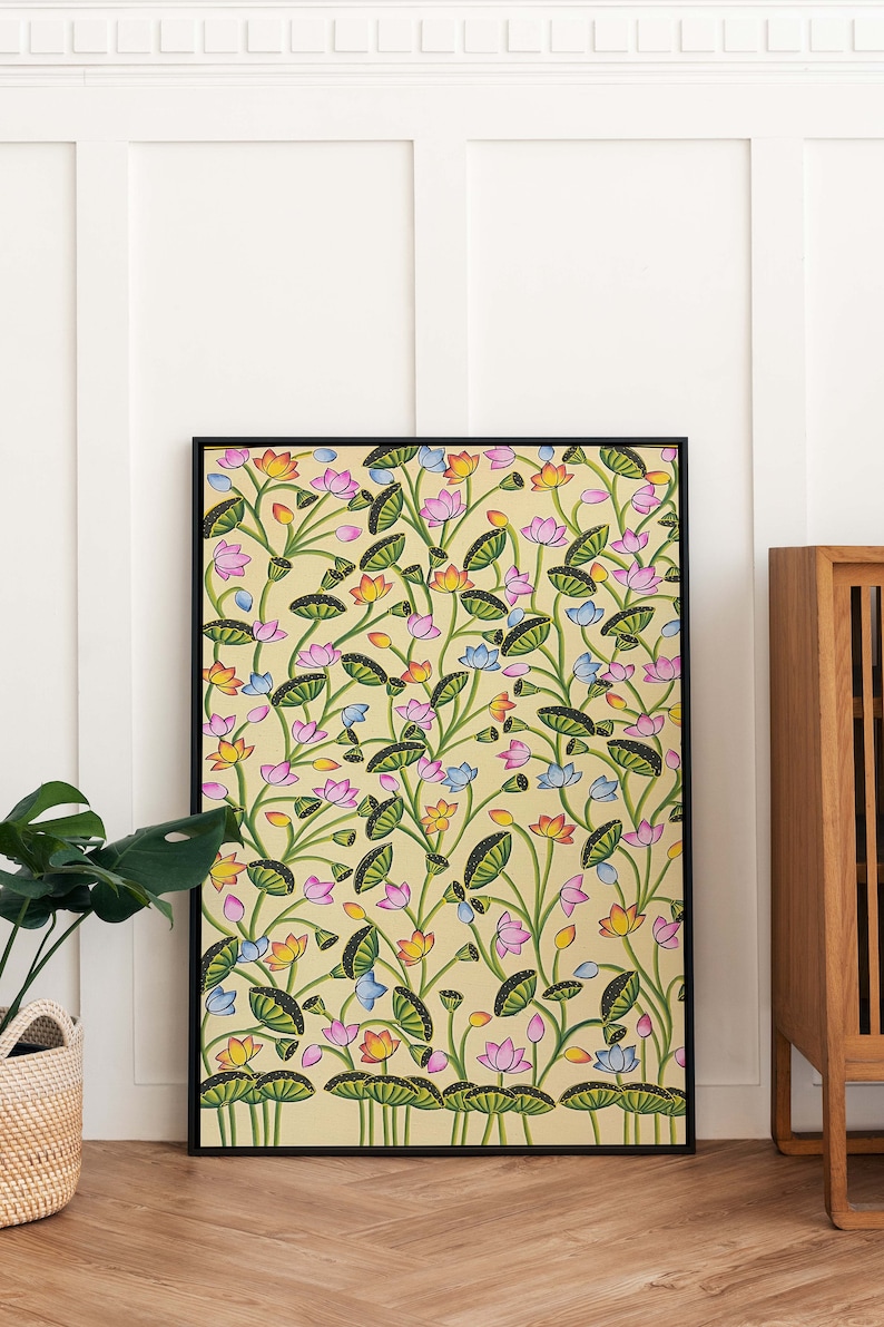 May include: A framed painting of a floral pattern with pink, blue, orange, and yellow flowers on a light yellow background. The flowers are surrounded by green leaves and stems.