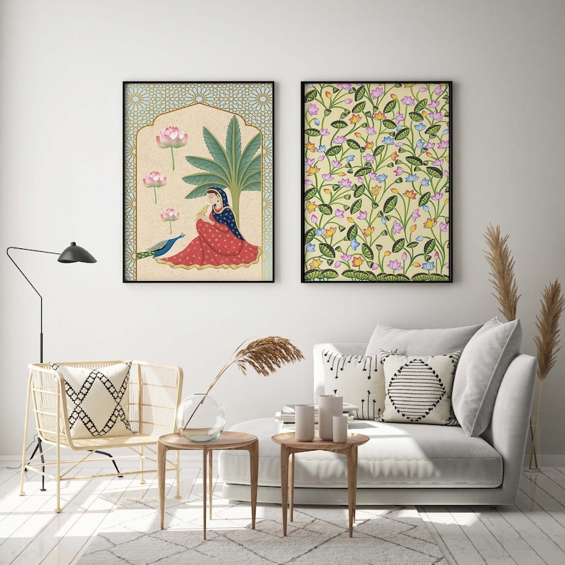 May include: Two framed illustrations of Indian art. The first illustration depicts a woman in a red and blue dress sitting with a peacock. The second illustration depicts a floral pattern with pink, yellow, and blue flowers.
