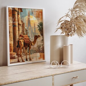 May include: A framed painting of a camel standing in front of an ancient Egyptian temple. The camel is brown with a saddle and is looking to the right. The temple is made of stone and has tall columns. The painting is set against a background of a sunset.