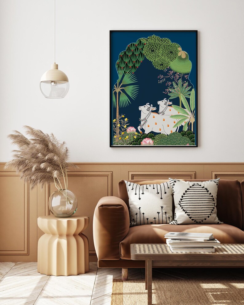 May include: A framed illustration of two white cows with orange markings standing in a lush green forest with a blue background. The cows are adorned with floral garlands. The forest is depicted in a stylized manner with palm trees and other tropical plants.