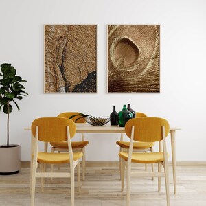 May include: A dining room table with four yellow chairs, a black bowl, and green glass bottles. Two framed pictures hang on the wall behind the table. One picture is of an elephant's face, and the other is of a swirling pattern.