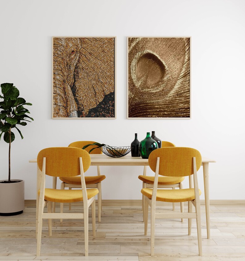 May include: A dining room table with four yellow chairs, a black bowl, and green glass bottles. Two framed pictures hang on the wall behind the table. One picture is of an elephant's face, and the other is of a swirling pattern.