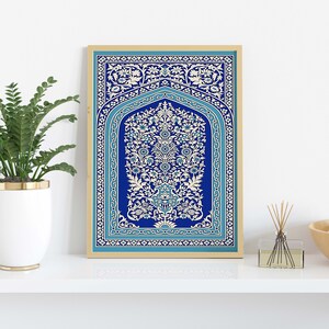 Puede incluir: Una impresi&oacute;n enmarcada de un dise&ntilde;o azul y blanco con un intrincado motivo floral. El dise&ntilde;o recuerda al arte isl&aacute;mico y presenta un arco central con un patr&oacute;n repetitivo de flores y hojas.