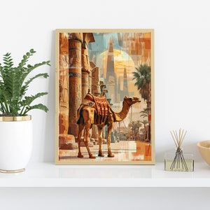 May include: A framed print of a camel walking through an ancient Egyptian city. The camel is brown with a saddle and is walking towards the right side of the image. The city is made up of tall, stone buildings with intricate carvings. The sky is a bright blue with a large, orange sun in the background.