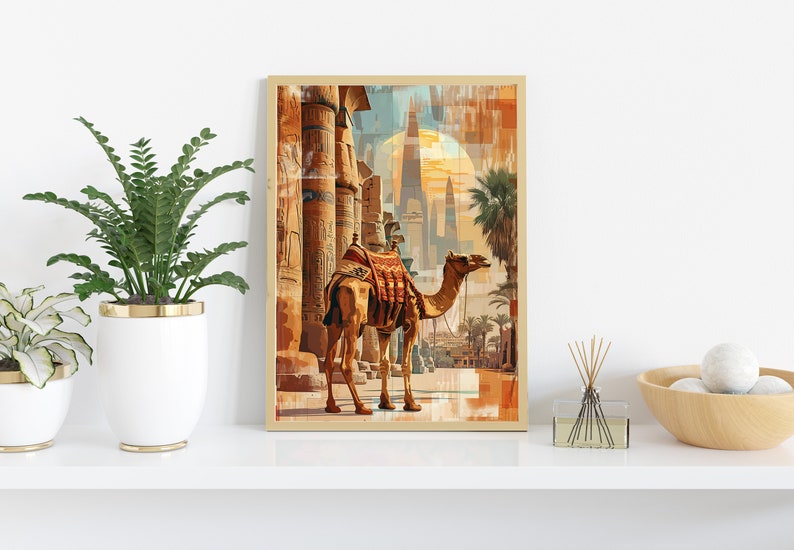 May include: A framed print of a camel walking through an ancient Egyptian city. The camel is brown with a saddle and is walking towards the right side of the image. The city is made up of tall, stone buildings with intricate carvings. The sky is a bright blue with a large, orange sun in the background.