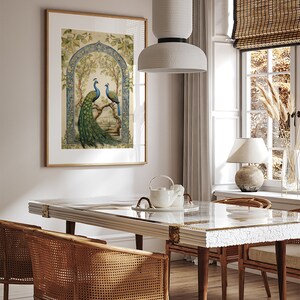 May include: A framed print of two peacocks perched on a branch in a lush green garden setting. The print features intricate details and a blue and green color scheme. The print is hanging on a wall in a dining room with a wooden table and chairs.