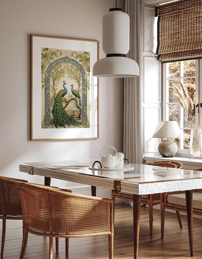 May include: A framed print of two peacocks perched on a branch in a lush green garden setting. The print features intricate details and a blue and green color scheme. The print is hanging on a wall in a dining room with a wooden table and chairs.