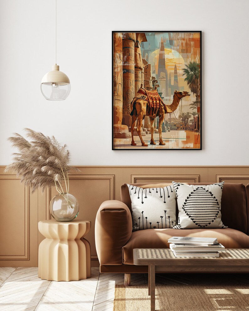 May include: A framed print of a camel standing in front of a large, ancient structure with pillars. The camel is brown and has a saddle on its back. The structure is made of stone and has intricate carvings. The background is a hazy blue and orange.