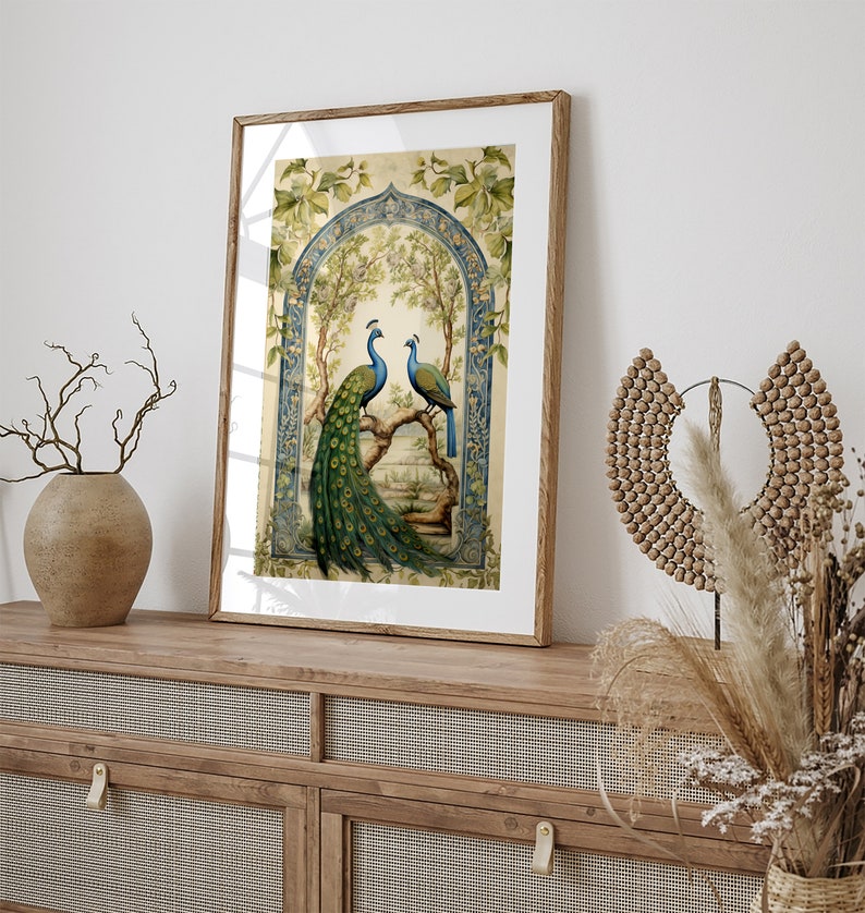 May include: A framed print of two peacocks perched on a branch in a decorative archway. The peacocks are blue and green with intricate tail feathers. The background is a light green with floral details.
