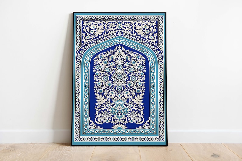 Puede incluir: Una impresi&oacute;n enmarcada de una alfombra de oraci&oacute;n isl&aacute;mica tradicional con intrincados patrones florales en blanco y azul sobre un fondo azul oscuro.