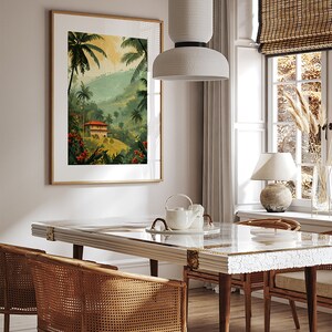 May include: A dining room with a white table and chairs, a white pendant light, and a framed print of a tropical landscape with a house in the distance.