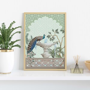 May include: A framed print of a peacock standing on a fountain in a green and white garden. The print has a decorative border with a geometric pattern.