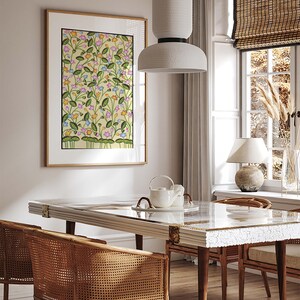 May include: A dining room with a white table and chairs with woven cane seats. The table has a glass top and a white ceramic teapot and cups on it. A framed print of a floral pattern hangs on the wall behind the table. A white pendant light hangs above the table.
