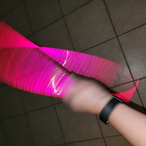 Puede incluir: Un juguete luminoso rosa y blanco que se hace girar en un movimiento circular, creando un efecto borroso.