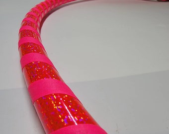 Può includere: Un cerchio rosa con nastro glitterato iridescente avvolto attorno. Il nastro è rosa con una finitura olografica.