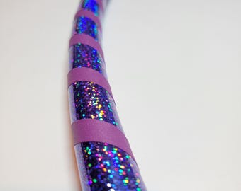 Può includere: Cerchio viola e glitter iridescente con un motivo a strisce diagonali. Il cerchio è in plastica e ha un diametro di circa 76 cm.