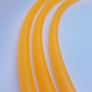 Puede incluir: Tres bandas de ejercicio de goma naranja, apiladas una encima de la otra, sobre un fondo blanco.