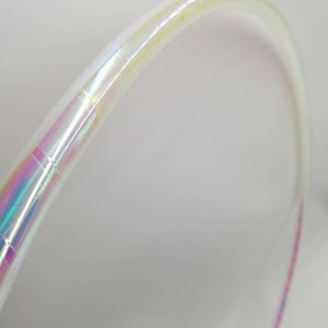 Op de afbeelding: Een witte, iriserende hoepel met een roze en blauwe streep. De hoepel is gemaakt van plastic en is flexibel.