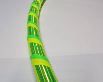 Può includere: Un cerchio iridescente verde e giallo con nastro verde e giallo avvolto attorno.