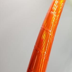 Puede incluir: Primer plano de un aro naranja iridiscente con una superficie texturizada.