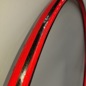 Puede incluir: Primer plano de una llanta de bicicleta roja con una franja negra en el centro.