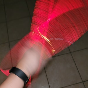 May include: A hand holding a red and yellow light-up toy that is being spun in a circle, creating a blur of red and yellow light.