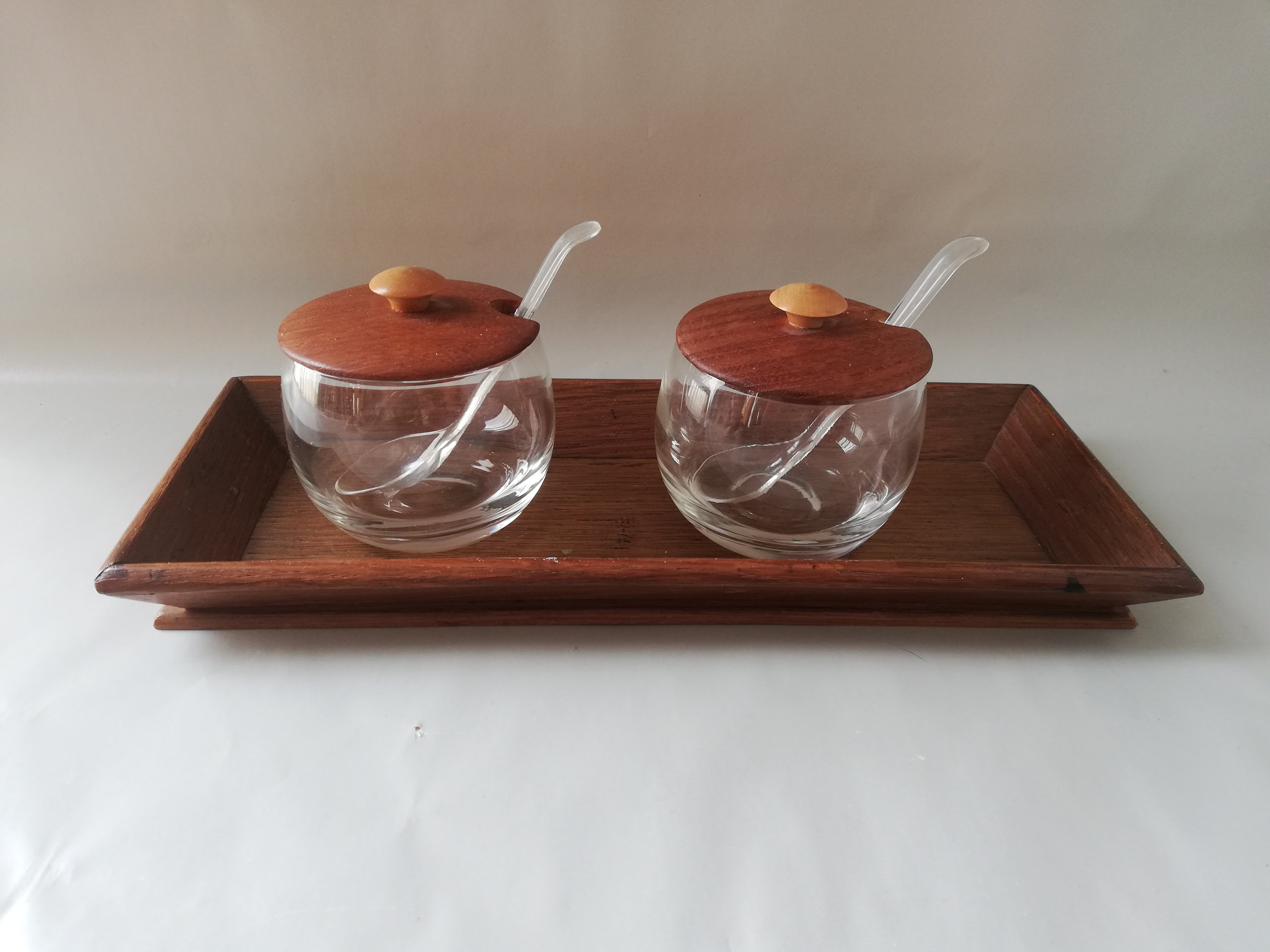 Glass jars with wooden lids and spoons for serving side dishes. Serving dishes for side dishes such as jam, ketchup, horseradish or caviar.