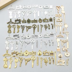 May include: A collection of sewing-themed charms in various metallic finishes. The charms include scissors, sewing machines, buttons, spools of yarn, and measuring tools. The charms are in silver, gold, and bronze tones, perfect for jewelry making or crafting projects.