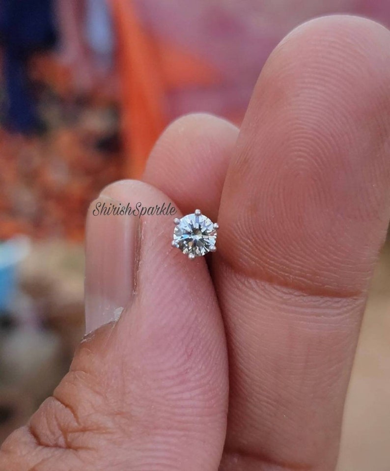 May include: A clear, round, sparkling nose ring with a silver setting.