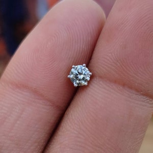 May include: A single round diamond gemstone set in a six-prong setting. The diamond is clear and sparkly.