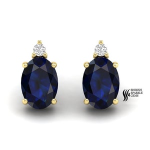 Pode incluir: Um par de brincos de safira ovalados engastados em ouro amarelo com um único acento de diamante em cada brinco.