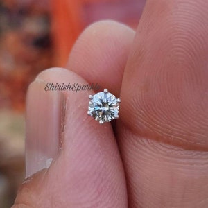 May include: A silver nose ring with a clear round gemstone.