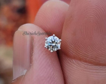 May include: A silver nose ring with a clear round gemstone.