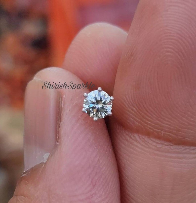 May include: A silver nose ring with a clear round gemstone.