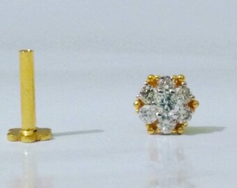 May include: A gold nose ring with a cluster of small, clear stones set in a flower shape.