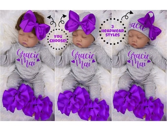 May include: A grey baby onesie with the name "Gracie Mai" in purple lettering and hearts. The baby is wearing a purple bow headband and a purple ruffle leg warmer set. The image shows three different headband styles to choose from.