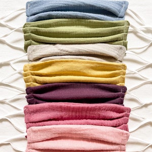May include: A 7 pack of face masks in various colors, including blue, green, beige, yellow, purple, pink, and light pink. The masks are made of a soft, breathable fabric and have elastic ear loops.
