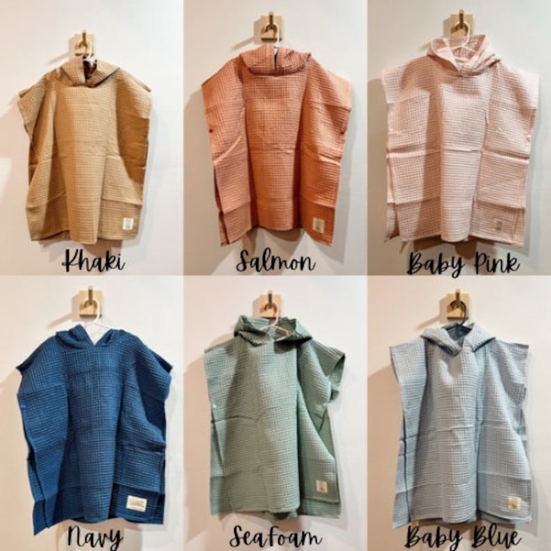 May include: Six hooded towels in different colors: khaki, salmon, baby pink, navy, seafoam, and baby blue. The towels are made of waffle weave fabric and have a hood with a button closure.