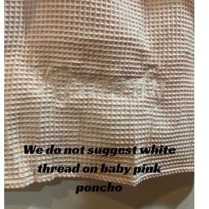 May include: A close-up of a pale pink waffle weave fabric with white embroidery. The text "We do not suggest white thread on baby pink poncho" is visible at the bottom of the image.