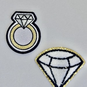 Puede incluir: Dos parches para planchar que representan un anillo de diamantes y un diamante. El parche del anillo tiene un contorno dorado y el parche del diamante tiene un contorno de purpurina dorada.