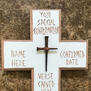 May include: White wooden cross with a rustic brown finish. The cross has a nail in the center and the words "YOUR SPECIAL CONFIRMATION" at the top, "NAME HERE" on the left, "CONFIRMED DATE" on the right, and "VERSE CARVED HERE UP TO TWENTY-FIVE WORDS" on the bottom.