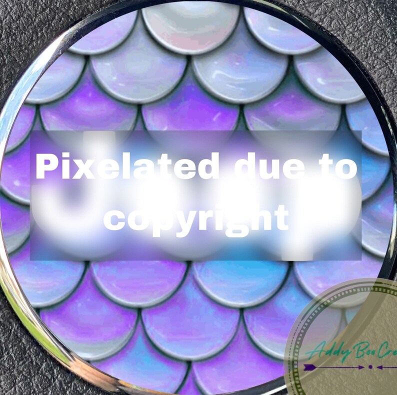 Pu&ograve; includere: Primo piano di un design rotondo di squame di sirena iridescenti di colore viola e blu. L'immagine &egrave; pixelata a causa dei diritti d'autore.