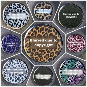 May include: Nine round coasters with a leopard print design. Each coaster has a silver rim and a white text overlay that reads "Blurred due to copyright".