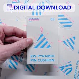 May include: A white card with the text "ZW PYRAMID PIN CUSHION" in blue. The card features a blue and pink pyramid design. The words "DIGITAL DOWNLOAD" are at the top. The card is held by a hand.